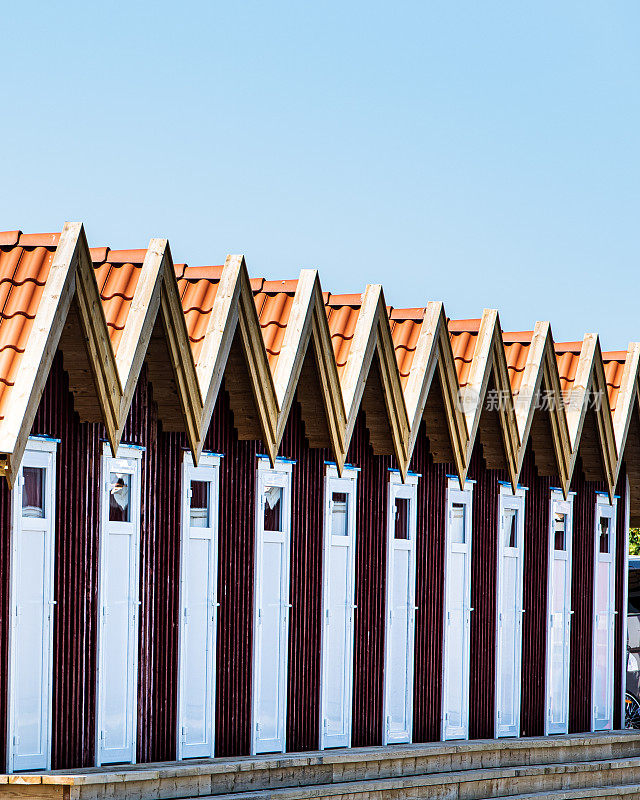Closeup of Scandinavian architecture with row of red summerhouses in Fotö hamn. Detail of Swedish buildings with a series of typical summer houses or sommarstuga in Foto Harbour. Bohuslän, Götaland